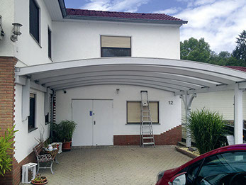 Weiße Rundbogenüberdachung, anschließend an die Hausfassade